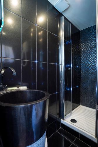 a black bathroom with a tub and a shower at Hôtel Du Brésil in Paris