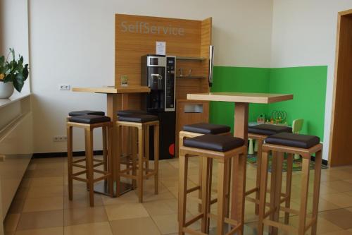 a kitchen with three bar stools and a refrigerator at Kloster Neustadt in Neustadt an der Weinstraße