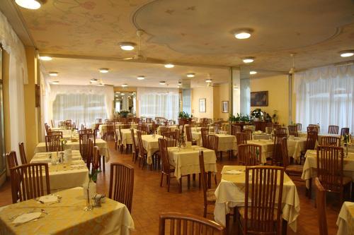 a dining room with tables and chairs with white tablecloths at Hotel Diana in Grado