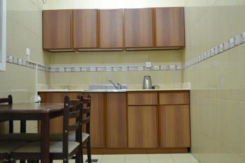 uma cozinha com armários de madeira, uma mesa e um lavatório em Nojoom Yanbu em Iambo