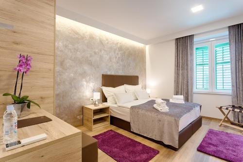 sypialnia z łóżkiem i stołem z fioletowymi dywanami w obiekcie Central Pearl by Nono Ban Rooms w Splicie