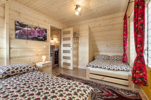 ホホウフにあるChocholowskie Domkiのログキャビン内のベッドルーム1室(ベッド2台付)