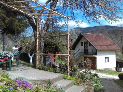 a garden with a table and a house with a tree at Apartman Ana in Mokra Gora
