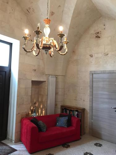 a living room with a red couch and a chandelier at Il Casolare Degli Ulivi in Oria