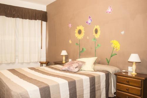 a bedroom with a bed with sunflowers on the wall at Residencial Los Silos in Los Silos
