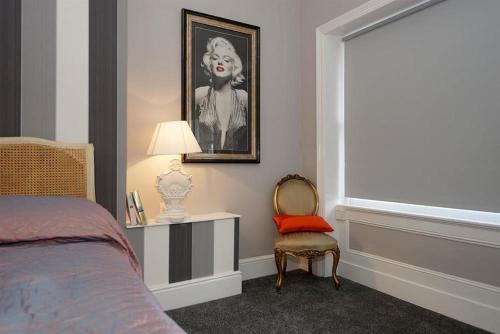 a bedroom with a bed and a chair and a window at Cornerhouse Apartments Llandudno in Llandudno