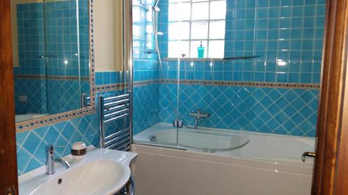 a blue tiled bathroom with a sink and a tub at Affittacamere Olimpo in Palermo