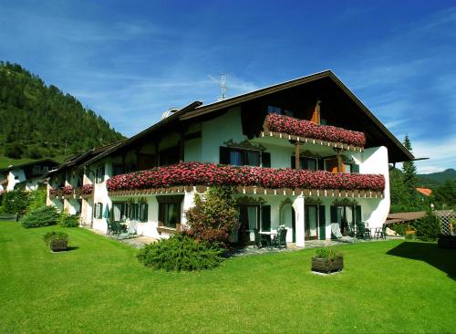 a house with red flowers on the side of it at Appartementhaus Alpenrose in Wallgau
