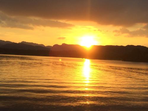 a sunset on the water with mountains in the background at Invergarry Room Only Guest House For Adults in Windermere