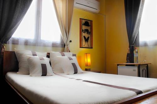 a large bed with white pillows and a window at Iarimbato Hotel in Antananarivo
