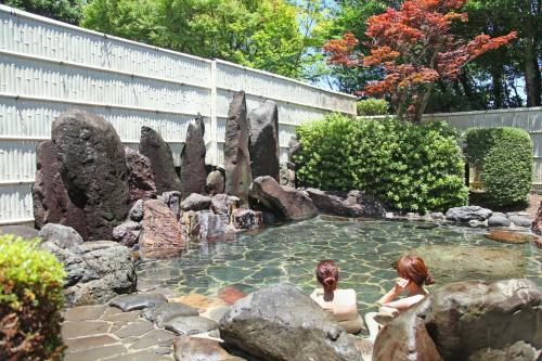 two women sitting in a pool of water with rocks at Chikurakutei in Minami Aso