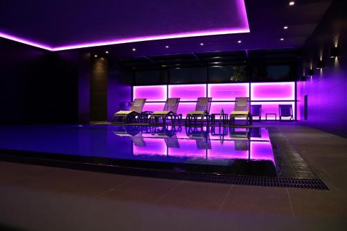 a group of chairs and a pool with purple lights at Privilege Hotel & Spa in Tirana