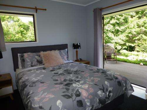 a bedroom with a bed and a window with a patio at Tranquil Private Rural Retreat in Tauranga