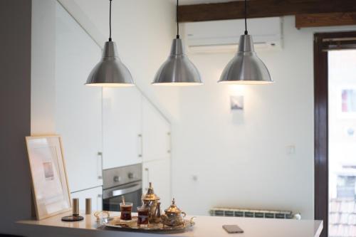 a kitchen with three lights hanging over a counter at Old Town Apartment in Sarajevo