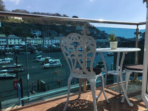 einen Tisch und Stühle auf einem Balkon mit Blick auf den Yachthafen in der Unterkunft Shellseekers Guest House in Looe