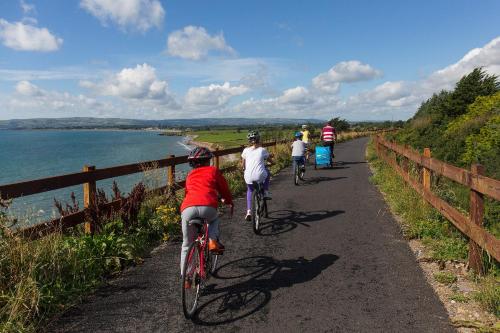 a group of people riding bikes down a path by the water at The Fitzwilton Hotel in Waterford