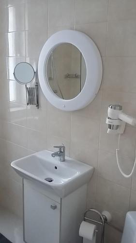 a white bathroom with a sink and a mirror at La Caramidari Bucuresti in Bucharest