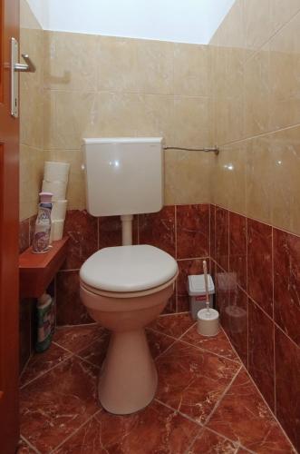 a bathroom with a toilet in a tiled room at Bíbor Apartman in Gyula