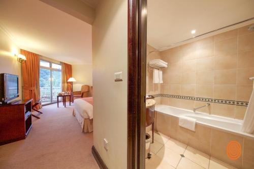 a bathroom with a bath tub and a bedroom at Lake Kivu Serena Hotel in Gisenyi