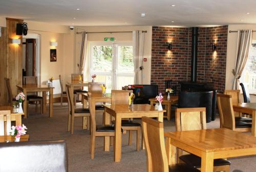 a restaurant with wooden tables and chairs and a brick wall at Royal Lodge in Symonds Yat
