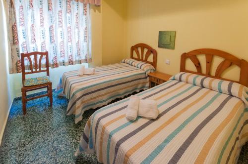 Playa de MiramarにあるPandora 1のベッド2台と椅子が備わる客室です。
