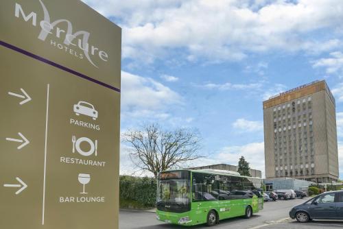 a green bus is parked next to a building at Mercure Paris Orly Rungis Aéroport in Rungis
