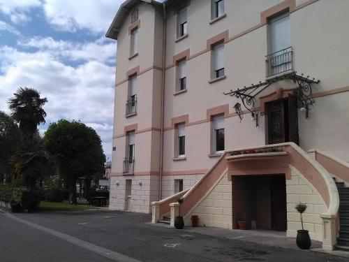 a large pink building with a staircase in front of it at Hôtel du Parc in Salies-du-Salat