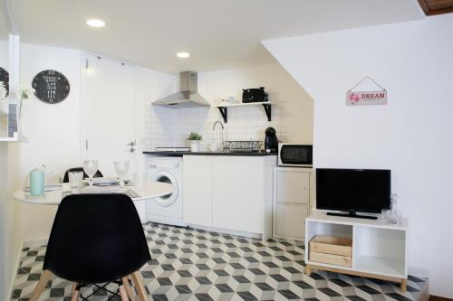 biała kuchnia ze stołem i telewizorem w obiekcie Alfama Apartment Rose - Guitarra w Lizbonie