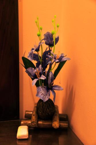 a vase filled with purple flowers on a table at Anon Rest in Dambulla