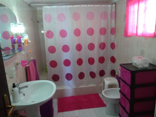 a bathroom with a pink and white shower curtain and a toilet at Val's Place in Praia da Vitória