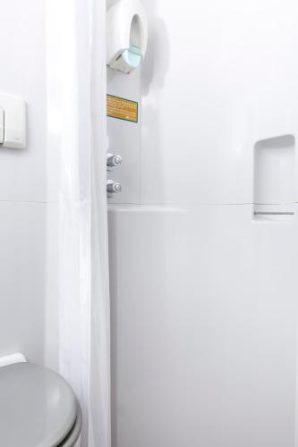une salle de bain blanche avec toilettes et douche dans l'établissement Initial by Balladins Béthune, à Beuvry