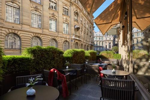 a patio area with tables, chairs and umbrellas at Le Pavillon des Lettres - Small Luxury Hotels of the World in Paris