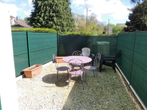 a patio with a table and chairs and a fence at le petit Vauquelin in Sommervieu