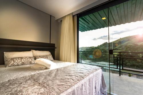 um quarto com uma cama e uma grande janela em Hotel Fazenda Terra dos Sonhos em Bueno Brandão