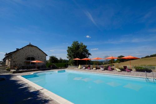 una gran piscina con sillas y sombrillas en Logis Hotel Le Relais du Teulet, en Goulles