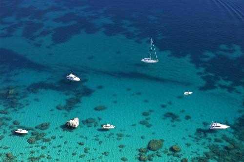 a group of boats floating in the ocean at Club Esse Cala Bitta in Baja Sardinia