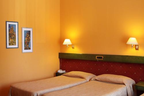 a hotel room with two beds and two lamps at Eurohotel in Piacenza