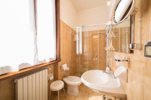 a bathroom with a sink and a toilet and a mirror at Hotel Carancini in Salsomaggiore Terme