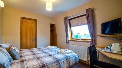 
a bedroom with a television and a bed at Kilcumin Guest House in Inverness
