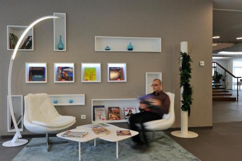 a man sitting in a chair in a waiting room at Novotel Avignon Centre in Avignon