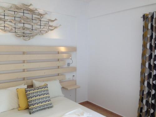 a bedroom with a white bed with a wooden headboard at Yanna Asteri Suites in Ornos