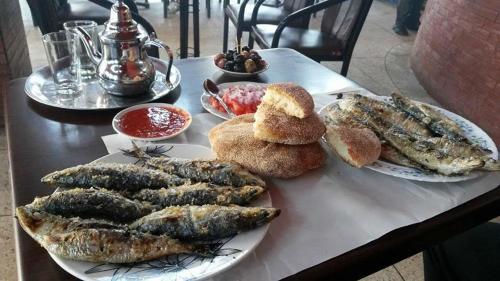 a table with plates of fish and bread on it at Etablissement moderne in Safi
