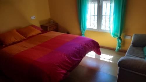 リンコン・デ・ラ・ビクトリアにあるHabitación Privada en Casa Compartida sobre el Marのカラフルなベッドと窓付きのベッドルーム1室が備わります。