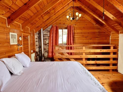 a bedroom with a white bed in a wooden room at Nofesh Ne'eman in Amirim