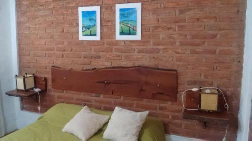 a bedroom with a brick wall and a green bed with pillows at Cabañas Molinos de Vientos in Potrero de los Funes
