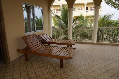 a wooden bench sitting on a porch at Ramaya Auberge Espagnole in Grand-Popo