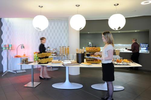a woman standing at a counter with a buffet of food at Novotel Avignon Centre in Avignon