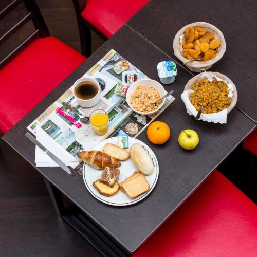 ein Tisch mit Tellern mit Frühstücksspeisen und Orangensaft in der Unterkunft Initial by Balladins Béthune in Beuvry