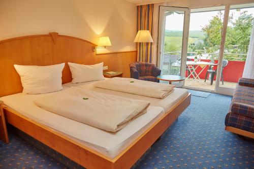 レーヴェンシュタインにあるFlair Hotel Landgasthof Rogerのベッドとバルコニー付きのホテルルーム