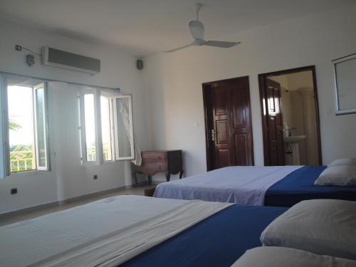 a bedroom with two beds and two windows at Ramaya Auberge Espagnole in Grand-Popo